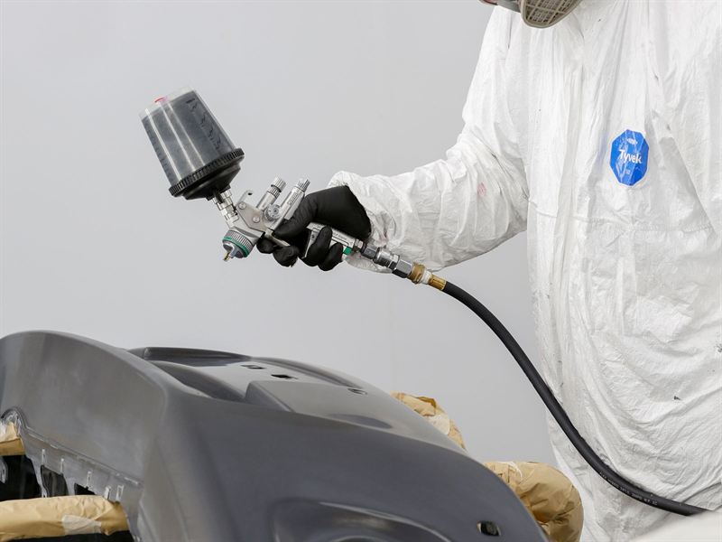 Técnico aplicando pintura automotriz en el taller de enderezado y pintura